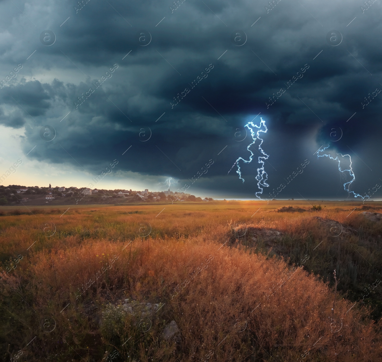 Image of Picturesque thunderstorm over field near village. Dark cloudy sky with lightnings