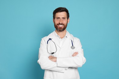 Photo of Happy doctor with stethoscope on light blue background