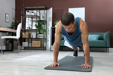 Photo of Handsome man doing high plank exercise on floor at home