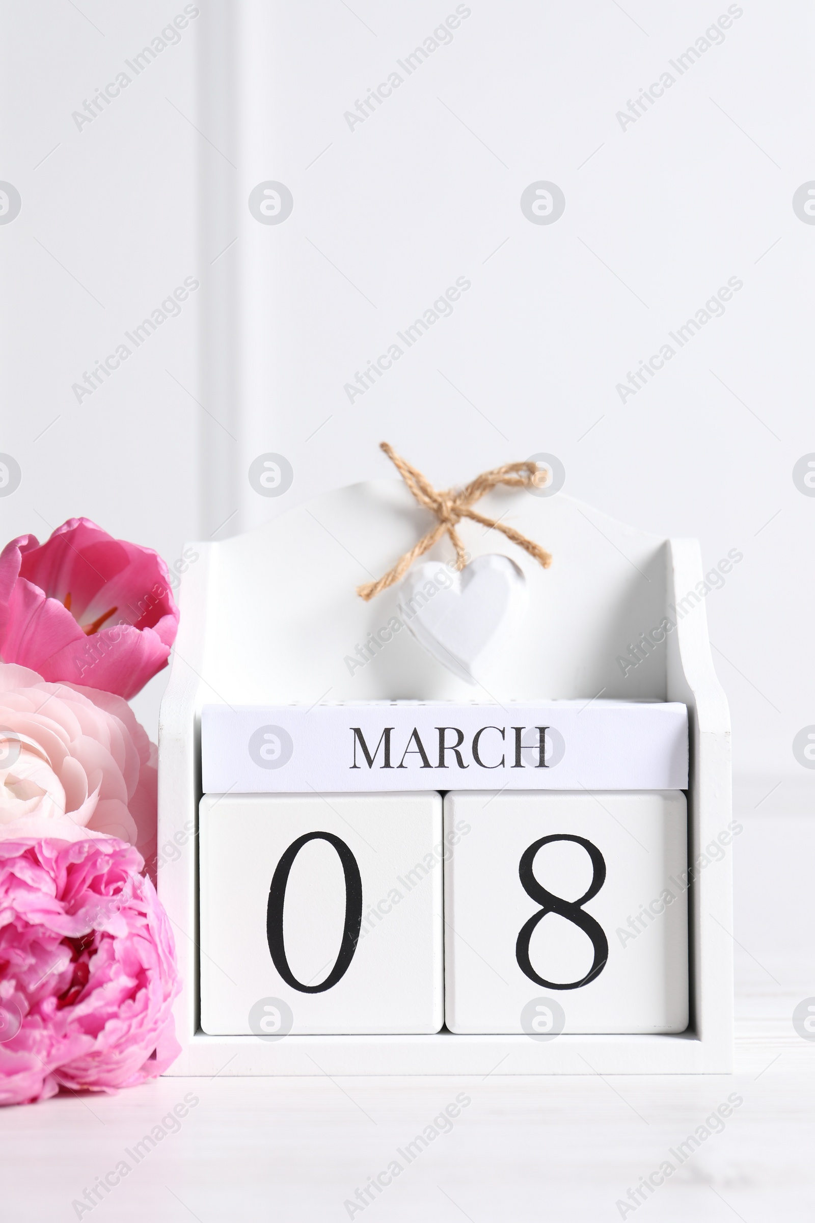 Photo of International Women's day - 8th of March. Wooden block calendar and beautiful flowers on white table