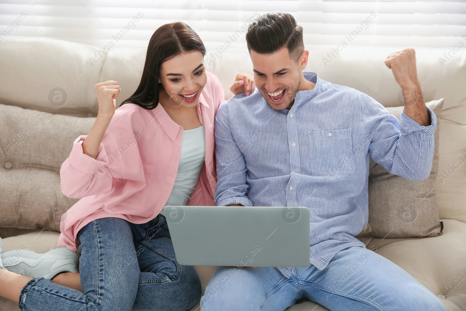 Photo of Emotional couple participating in online auction using laptop at home