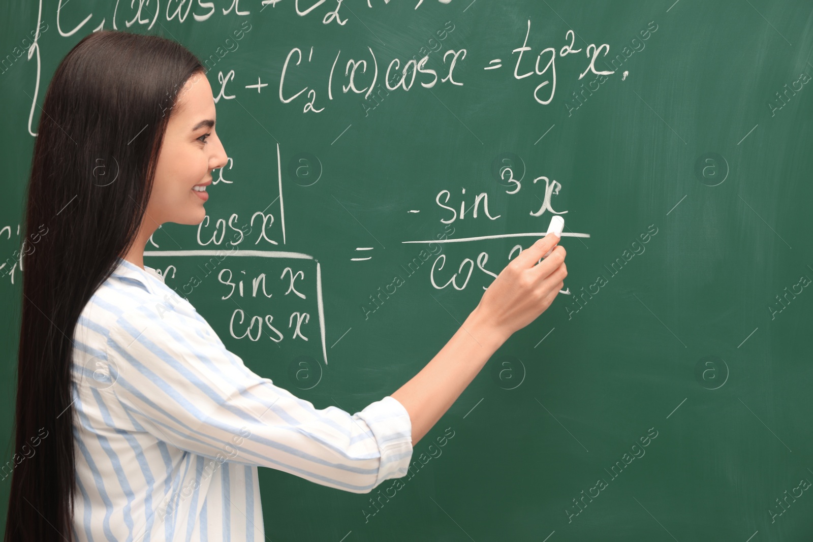 Photo of Happy teacher explaining mathematics at chalkboard in classroom