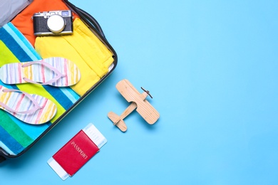Photo of Open suitcase and beach objects on blue background, flat lay. Space for text