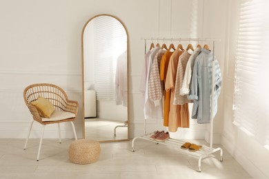 Photo of Modern dressing room interior with stylish clothes, shoes and large mirror