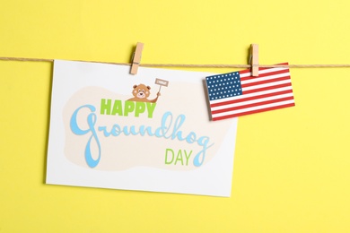 Happy Groundhog Day greeting card and American flag hanging on yellow background