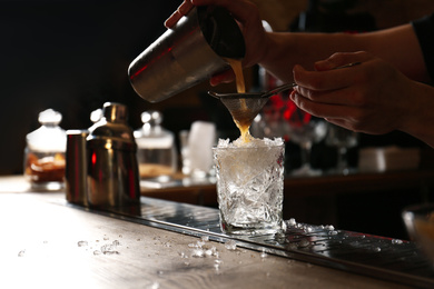 Bartender preparing fresh alcoholic cocktail at bar counter, closeup