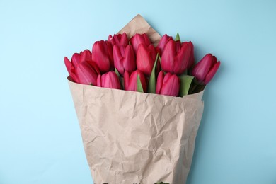 Photo of Bouquet of beautiful tulips on light blue background, top view