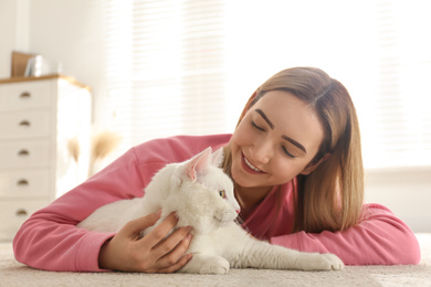 Young woman with her beautiful white cat at home. Fluffy pet