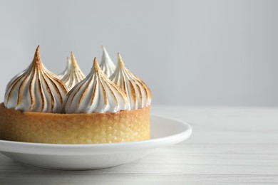 Photo of Tasty dessert. Tartlet with meringue on white wooden table, closeup. Space for text