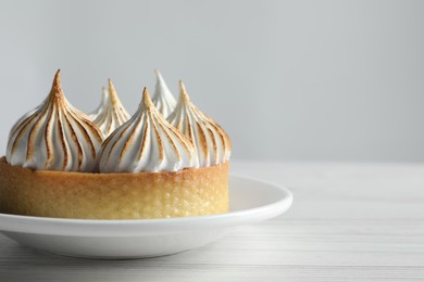 Tasty dessert. Tartlet with meringue on white wooden table, closeup. Space for text