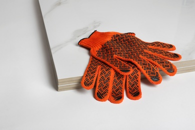 Stack of ceramic tiles and gloves on white background. Space for text