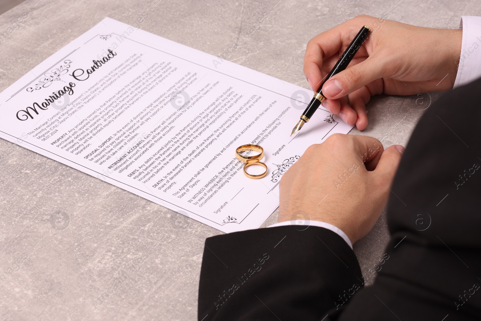 Photo of Man signing marriage contract at light grey table, closeup