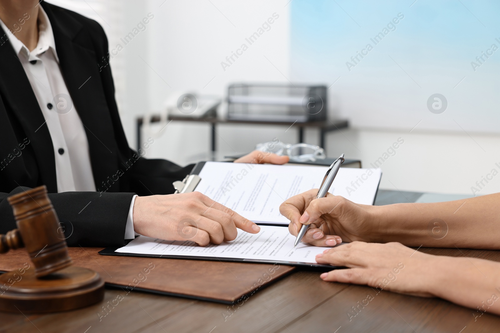 Photo of Senior woman signing document in lawyer's office, closeup