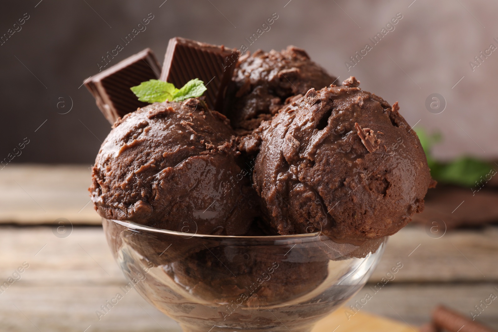 Photo of Tasty chocolate ice cream with mint in glass dessert bowl on table, closeup