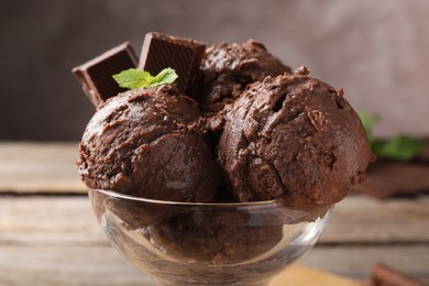 Photo of Tasty chocolate ice cream with mint in glass dessert bowl on table, closeup
