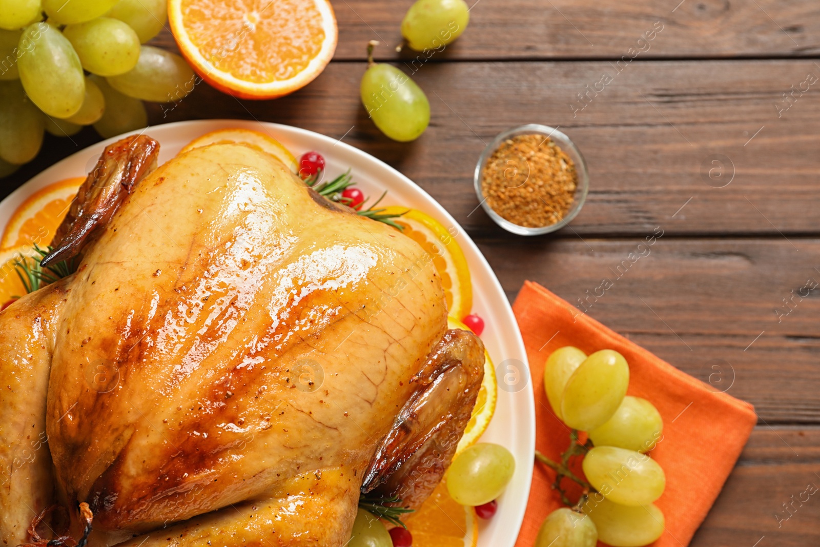 Photo of Platter of cooked turkey with garnish on wooden background, flat lay. Space for text