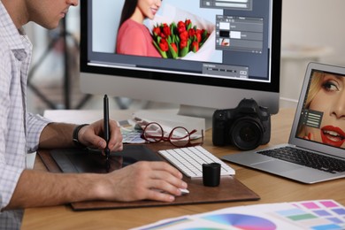 Photo of Professional retoucher working on graphic tablet at table, closeup