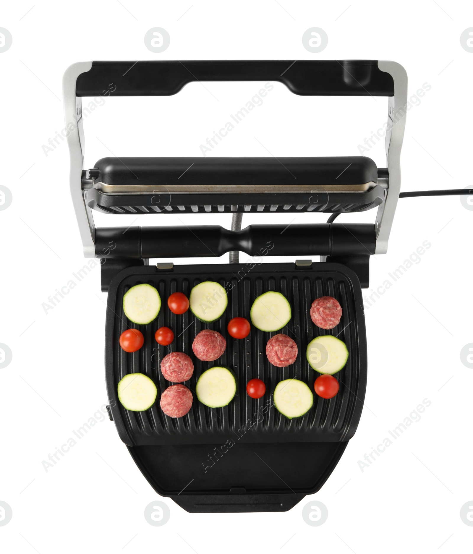 Photo of Electric grill with meat balls, zucchini and tomatoes isolated on white, top view