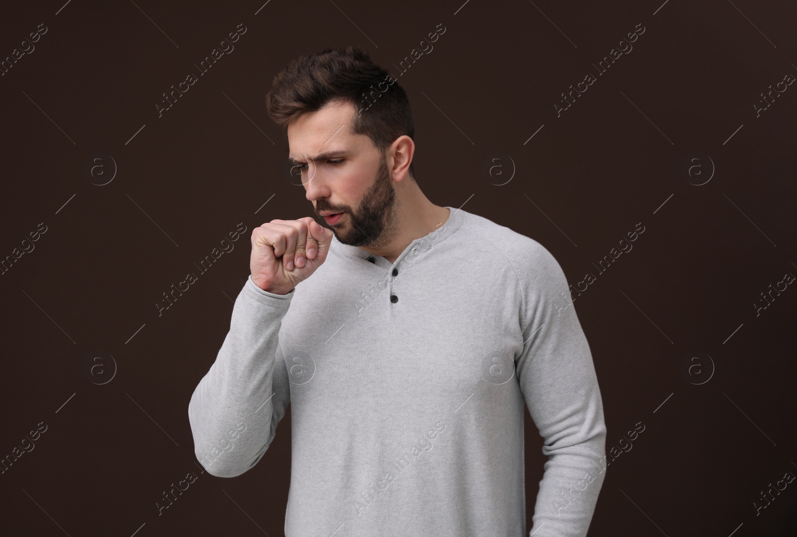 Photo of Sick man coughing on brown background. Cold symptoms