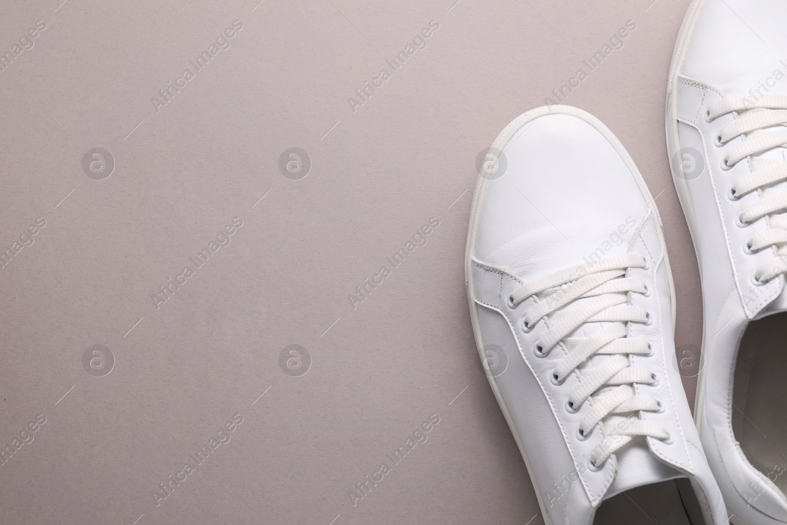 Photo of Pair of stylish white sneakers on grey background, top view. Space for text