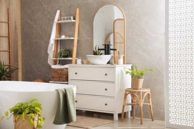 Modern white tub and chest of drawers with sink in bathroom. Interior design