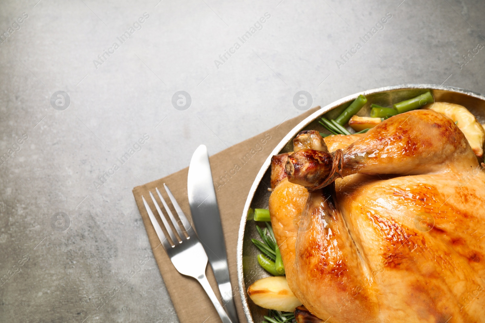 Photo of Delicious cooked turkey with garnish on grey table, top view with space for text. Thanksgiving Day celebration