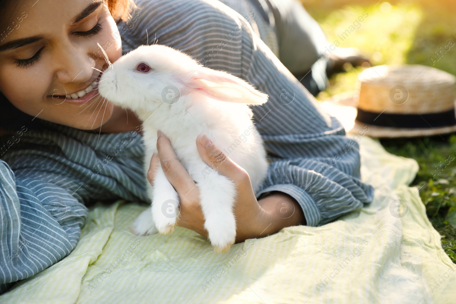 Photo of Happy woman with cute rabbit on green grass outdoors, closeup