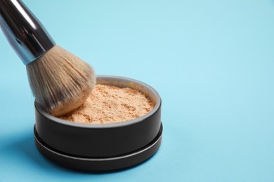 Photo of Applying face powder on brush on light blue background, space for text