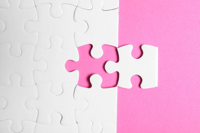 Photo of Blank white puzzle with separated piece on pink background, flat lay