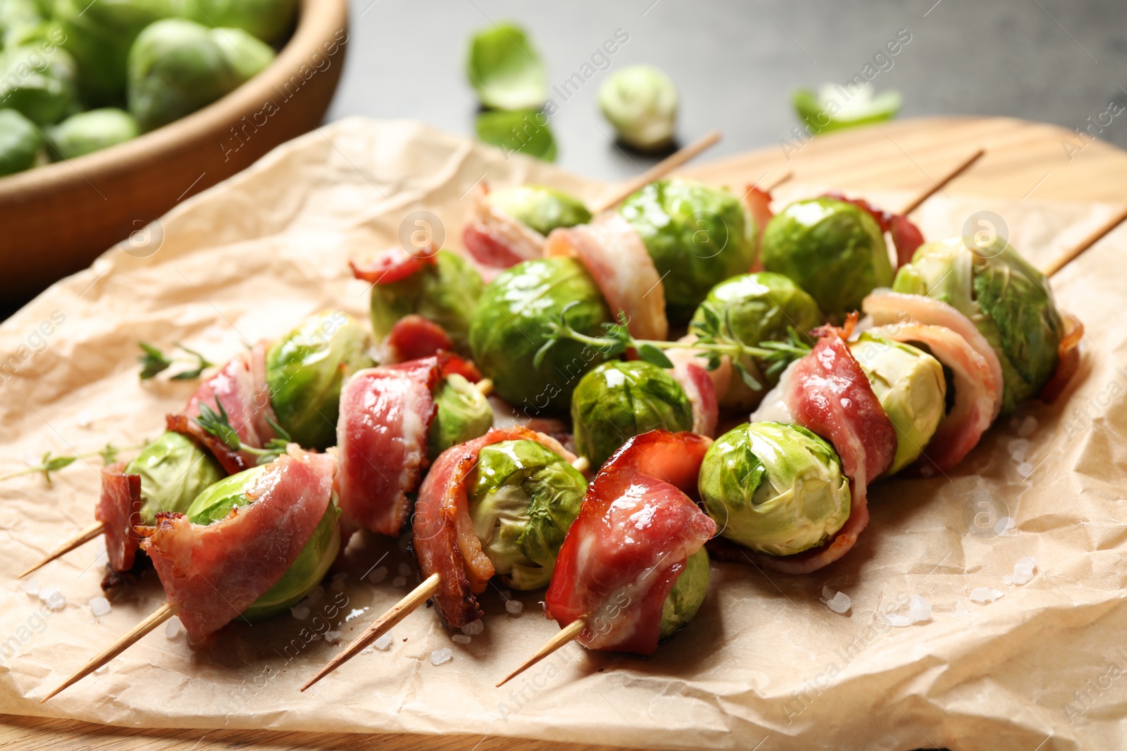 Photo of Skewers with delicious Brussels sprouts and bacon on table