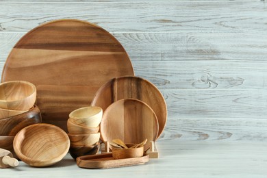 Set of clean wooden dishware and utensils on table. Space for text