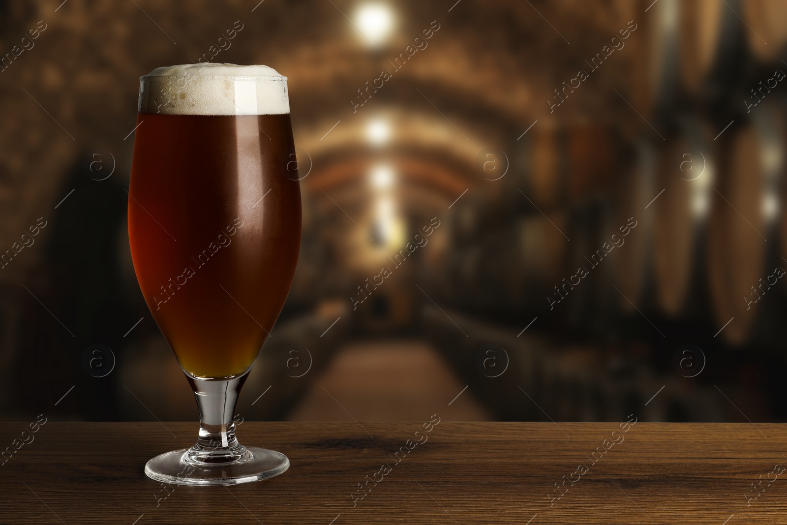 Image of Glass with fresh beer on wooden table in cellar, space for text