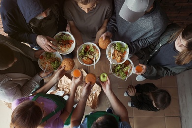 Photo of Poor people with plates of food indoors, view from above