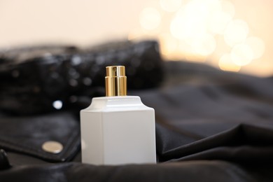 Photo of Bottle of perfume on black leather jacket, closeup