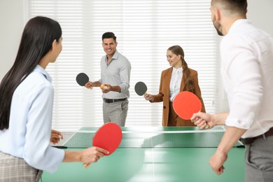 Business people playing ping pong in office