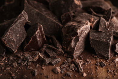 Pieces of dark chocolate on wooden table, closeup