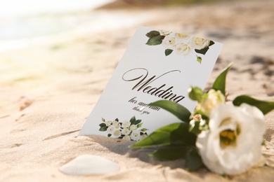 Photo of Wedding invitation and beautiful flower on sandy beach