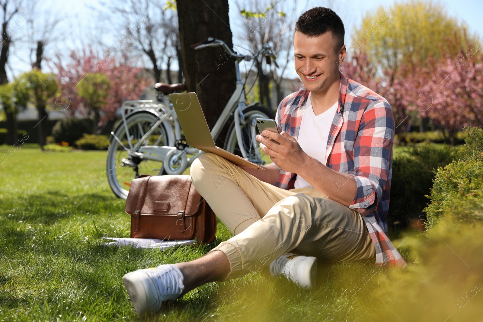 Photo of Man with smartphone and laptop working in park