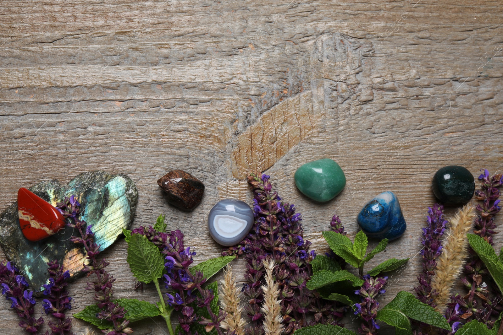 Photo of Flat lay composition with different gemstones and healing herbs on wooden table, space for text