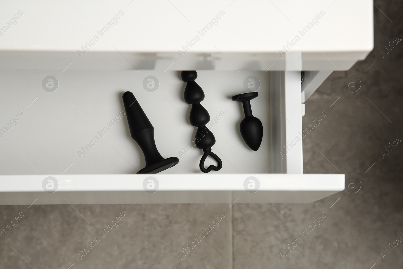 Photo of Black anal plugs and beads in drawer indoors, top view. Sex toys