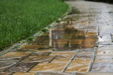 Photo of Puddle after rain on street tiles outdoors, closeup