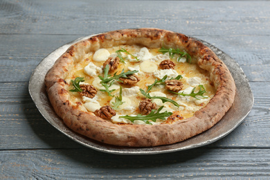 Photo of Delicious cheese pizza with walnuts and arugula on grey wooden table, closeup