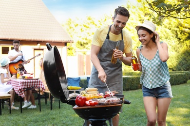 Photo of Young man and woman near barbecue grill outdoors
