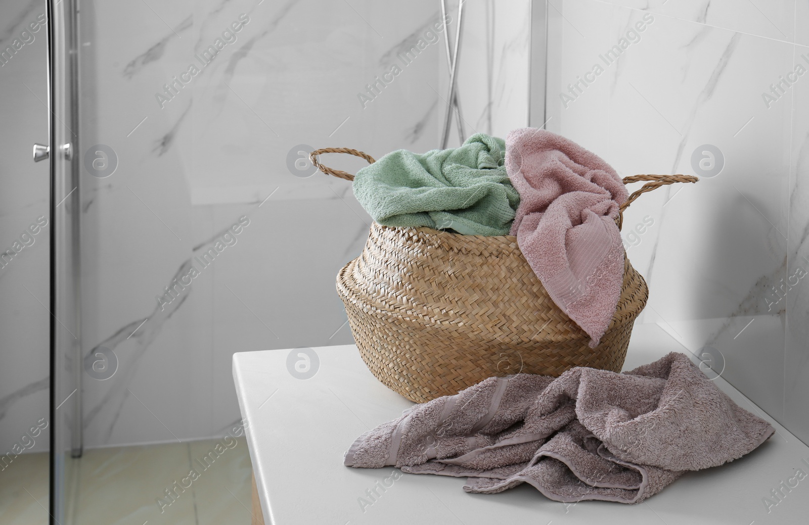 Photo of Wicker laundry basket with towels on countertop in bathroom. Space for text
