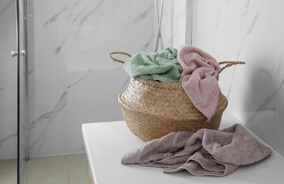Photo of Wicker laundry basket with towels on countertop in bathroom. Space for text