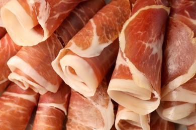 Photo of Rolled slices of delicious jamon as background, closeup