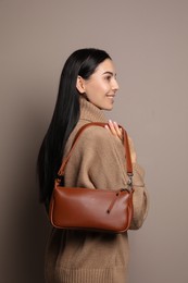 Photo of Fashionable young woman with stylish bag on beige background