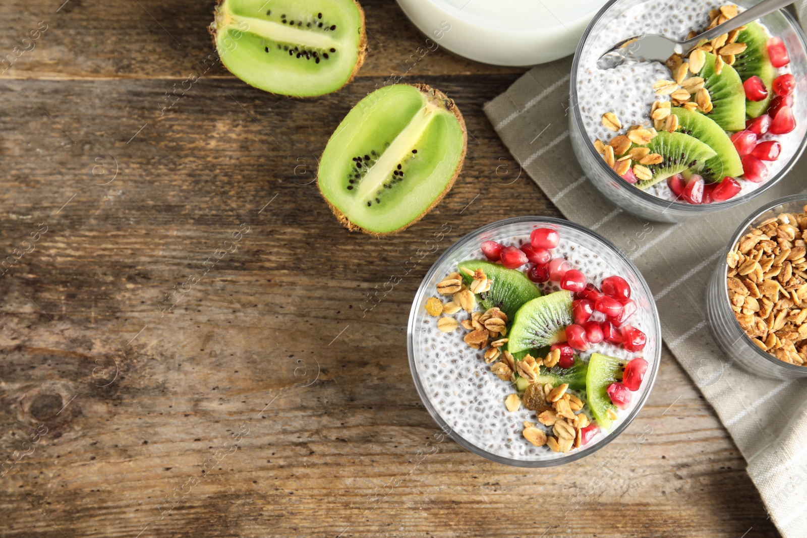 Photo of Tasty chia seed pudding with granola, kiwi and pomegranate on table, flat lay. Space for text