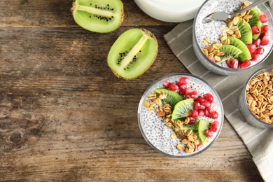 Tasty chia seed pudding with granola, kiwi and pomegranate on table, flat lay. Space for text