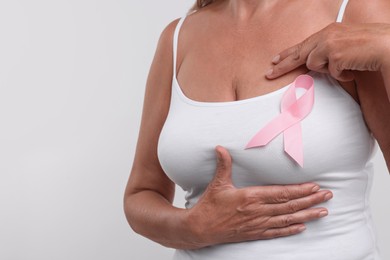 Photo of Woman with pink ribbon on white background, closeup and space for text. Breast cancer awareness